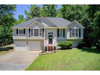 Charming home featuring a manicured lawn, two-car garage, and classic architectural details at 407 Yellowstone Dr, Powder Springs, GA 30127