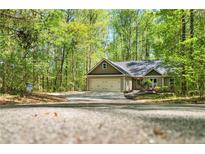 Charming home with a two-car garage and a large driveway surrounded by lush trees at 191 Orchard Dr, Canton, GA 30115