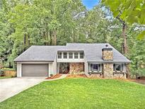 Charming home featuring stone accents, a two-car garage, and a well-manicured front lawn at 2435 Roxburgh Dr, Roswell, GA 30076
