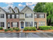 Inviting townhome featuring a well-maintained lawn, blue door, and symmetrical black shutters at 1203 Penhurst Way, Lawrenceville, GA 30043