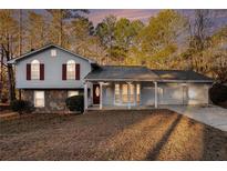 Charming two-story home with light blue siding, stone accents, and an attached three-car garage at 3448 Great Meadows Ct, Lithonia, GA 30038