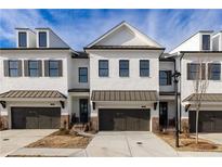 Charming white brick townhomes with modern design, featuring a two-car garage and covered entryway at 706 Dodd Ln # 157, Buford, GA 30518