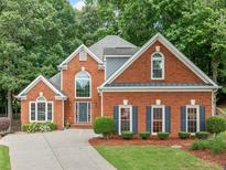 Stately two-story brick home with mature trees, manicured lawn, and a welcoming front entrance at 1440 Boundary Blvd, Suwanee, GA 30024