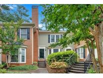 Charming townhome featuring a brick chimney, mature landscaping, and a welcoming front entrance at 4 Mount Vernon Cir, Atlanta, GA 30338