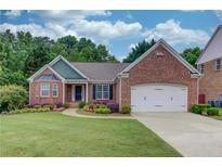 Charming brick home with manicured lawn, colorful flowerbeds, and a two-car garage at 4235 Crestwood Bend Cir, Buford, GA 30518