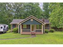 Charming home featuring a cozy front porch, complemented by lush greenery, and a neatly maintained lawn at 160 Northside Ave, Dallas, GA 30157