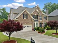 Charming brick home featuring a well-manicured lawn, lush landscaping, and a two-car garage, offering curb appeal at 580 River Valley Dr, Dacula, GA 30019