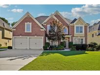 Charming brick home featuring a well-manicured lawn and a two-car garage, set under a bright, partly cloudy sky at 2909 Everson Ridge Ct, Snellville, GA 30039