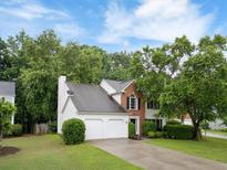Charming two-story home featuring a well-manicured lawn, lush trees, and a two-car garage at 10795 Glenbarr Dr, Johns Creek, GA 30097