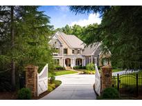 Stunning home with a long driveway, stone columns, white gates, and a mix of brick, stone and gray wood facade at 3639 Paper Mill Se Rd, Marietta, GA 30067