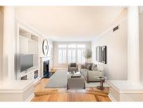 Bright living room with fireplace, built-in shelving, hardwood floors, and large windows at 220 Renaissance Ne Pkwy # 1105, Atlanta, GA 30308