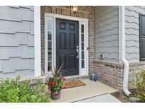 Inviting front entrance with a black door, brick accents, and a charming welcome mat at 4470 Madison Hall Dr, Cumming, GA 30028