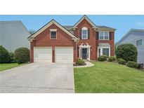 Charming two-story brick home features a well-manicured lawn and attached two-car garage at 153 Towey Trl, Woodstock, GA 30188