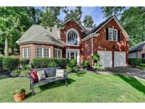 Charming brick home featuring a landscaped front yard, two-car garage, and an inviting front bench at 2633 Hanriva Ct, Dacula, GA 30019