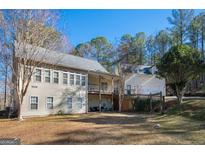 Spacious backyard view of the home with deck, mature trees, and outdoor seating area at 8245 Mill Run Trl, Whitesburg, GA 30185