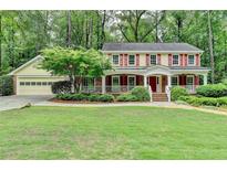 Charming two-story home featuring a welcoming front porch, red shutters, and a beautifully landscaped front yard at 5507 Martina Way, Dunwoody, GA 30338