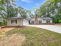Charming single-story home featuring a stone chimney, driveway, and manicured lawn at 2734 Amber Springs Way, Buford, GA 30519