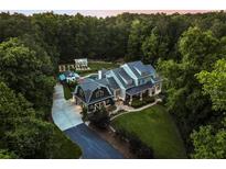 Stunning aerial view of estate home nestled among mature trees with detached garage and greenhouse at 390 Hembree Rd, Roswell, GA 30075