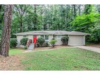 Charming single-story home with a red front door, surrounded by mature trees and a lush green lawn at 1715 Lee St, Decatur, GA 30035