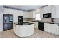 Spacious kitchen boasts white cabinets, black appliances, and an island with a cooktop at 5004 Duxford Se Dr, Smyrna, GA 30082