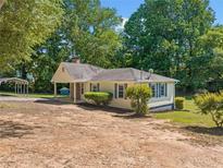Charming single-story home with a covered entrance, mature trees, and a side carport at 1554 Owens Store Road Rd, Canton, GA 30115
