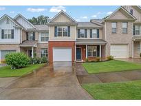Charming townhome featuring a one-car garage, brick accents, and well-maintained landscaping at 4055 Hill Station Ct, Sugar Hill, GA 30518