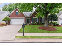 Charming brick home with a well-manicured lawn, mature tree, and a two-car garage at 6360 Waveland Dr, Cumming, GA 30040