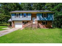 Charming two-story home with a brick facade, blue siding, and a well-manicured front lawn at 10 Canyon Cove Cv, Ellenwood, GA 30294