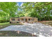 Single story home with a wide driveway, small front porch, and mature trees at 2017 S Deshon Rd, Lithonia, GA 30058