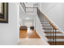 Bright foyer featuring hardwood floors, staircase with iron railings, and an open view to the living area at 3280 Stillhouse Se Ln # 410, Atlanta, GA 30339