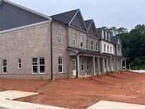New construction townhome with brick facade, multiple windows, covered entryway, and unfinished front yard at 3230 Cyrus Creek Dr, Kennesaw, GA 30152
