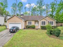 Charming single Gathering home showcasing a lush front yard, attached garage and inviting curb appeal at 1574 Glenfield Dr, Lawrenceville, GA 30043