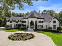 Stunning two-story home featuring a circular driveway, mature trees, and manicured lawn at 330 Longvue Ct, Johns Creek, GA 30097