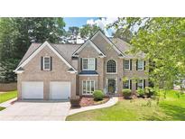 Charming brick two-story home with manicured lawn, two-car garage, and mature landscaping at 445 Sweet Ivy Ln, Lawrenceville, GA 30043