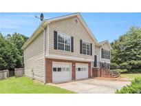 Two-story home with a two-car garage and neutral siding, brick facade and manicured lawn at 2175 Golden Valley Dr, Lawrenceville, GA 30043