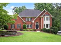 Charming two-story red brick home featuring manicured lawn, mature trees, and classic architectural details at 963 Bolingbrook Sw Dr, Marietta, GA 30064