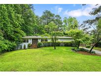 Charming single-story home featuring lush green lawn and mature trees, creating a serene curb appeal at 3317 Embry Hills Dr, Atlanta, GA 30341