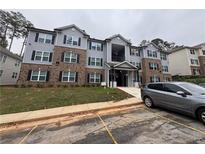 Modern apartment building with gray siding, brick accents, and a well-maintained lawn at 3204 Fairington Village Dr, Lithonia, GA 30038