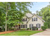 Charming two-story home with a lush front yard and welcoming porch with black shutters on windows at 5767 Wembley Dr, Douglasville, GA 30135