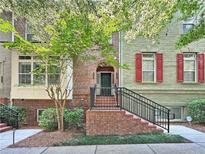 Charming townhouse with brick facade, red shutters, and an inviting front entrance with beautiful landscaping at 2766 Wander Ln, Alpharetta, GA 30022