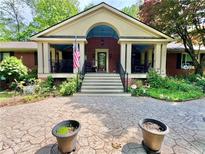 Charming brick home with a covered porch, manicured landscaping, and a patterned concrete driveway at 431 Keeler Woods Nw Dr, Marietta, GA 30064