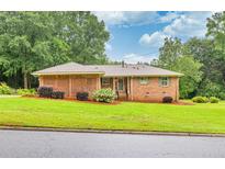 Charming brick home with manicured lawn, mature trees, and a welcoming entrance at 8140 Wood St Se, Covington, GA 30014