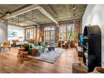 Spacious living room featuring hardwood floors, exposed brick, and large windows providing natural light and city views at 3235 Roswell Ne Rd # 508, Atlanta, GA 30305