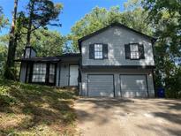 Charming two-story home with a two-car garage and a neutral color scheme surrounded by mature trees at 4064 Panola Woods Dr, Stonecrest, GA 30038