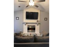 Cozy living room features a modern fireplace, vaulted ceilings, and a ceiling fan for added comfort at 4064 Panola Woods Dr, Stonecrest, GA 30038