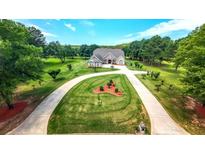 Stunning aerial view of a home with circular driveway, lush lawn, and beautifully landscaped grounds surrounded by mature trees at 100 Marshas Vineyard, Hampton, GA 30228