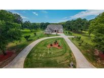 Expansive front yard with a circular driveway leading to a beautiful brick home, surrounded by mature trees and lush landscaping at 100 Marshas Vineyard, Hampton, GA 30228