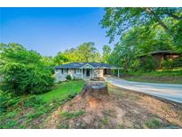 Charming single-story home with a covered parking, inviting curb appeal and lush green surroundings at 4457 Lincoln Jones Rd, Ellenwood, GA 30294