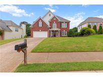 Charming two-story red brick home with manicured lawn and inviting front porch at 290 Bluff Oak Dr, Roswell, GA 30076