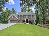 Beautiful two-story brick home featuring lush landscaping and a well-manicured lawn at 335 S Satinwood Pl, Roswell, GA 30076